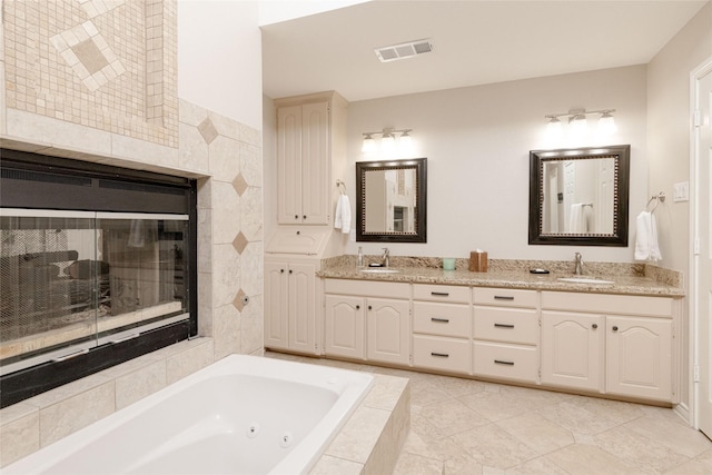 bathroom with visible vents, a sink, a jetted tub, and a tile fireplace