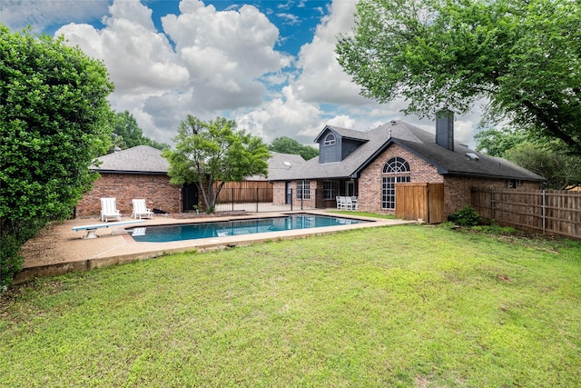 view of pool featuring fence, a diving board, a fenced in pool, a patio area, and a lawn