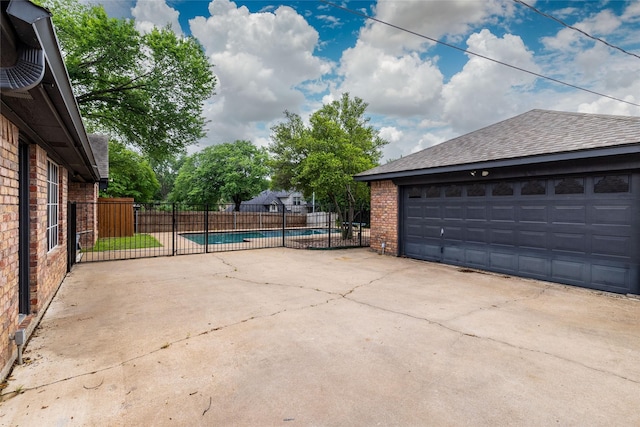 detached garage featuring fence and a fenced in pool