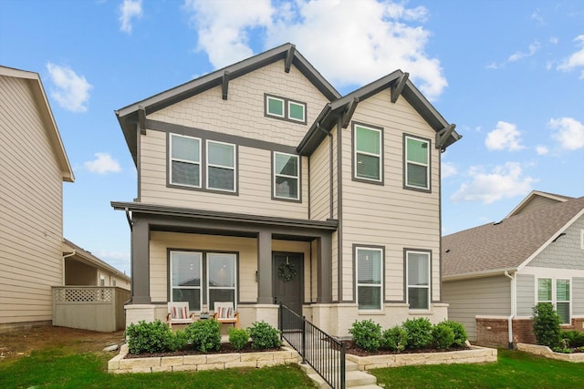 craftsman inspired home featuring a porch, fence, and a front yard