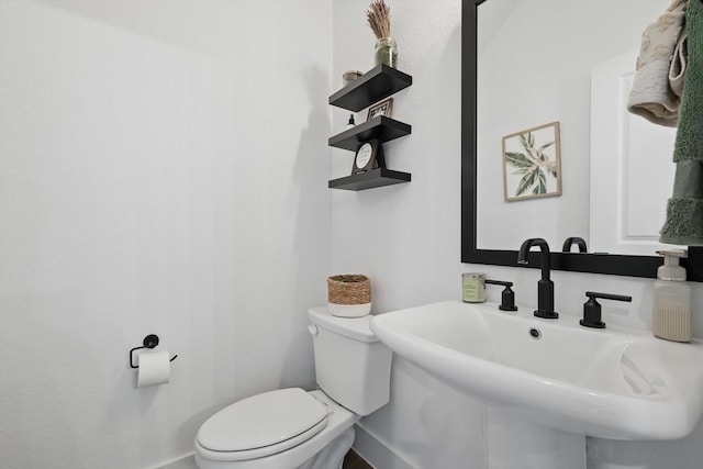 bathroom with toilet, baseboards, and a sink