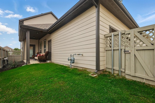 view of side of home featuring fence, a gate, and a yard