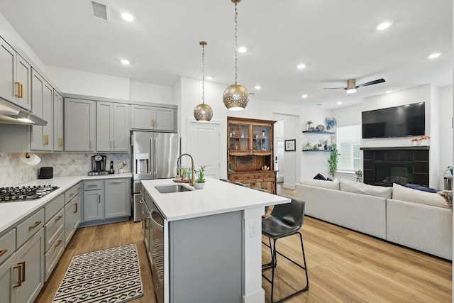 kitchen with ceiling fan, visible vents, a center island with sink, gray cabinetry, and light countertops