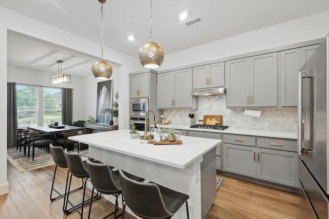 kitchen featuring visible vents, decorative backsplash, gray cabinetry, and stainless steel appliances