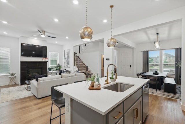 kitchen with a sink, light countertops, gray cabinets, and light wood-style floors