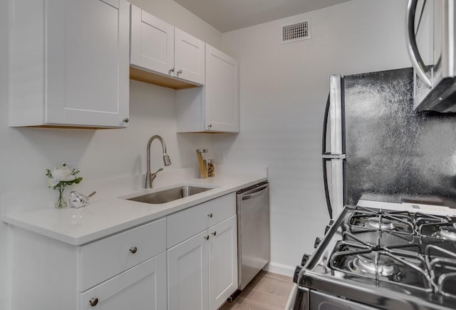 kitchen featuring visible vents, light countertops, white cabinetry, a sink, and stainless steel appliances