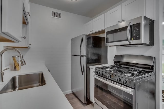 kitchen with visible vents, appliances with stainless steel finishes, a sink, light countertops, and white cabinetry