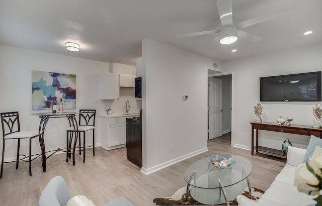 living room featuring visible vents, light wood-style floors, baseboards, ceiling fan, and recessed lighting
