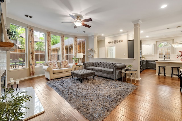 living room with baseboards, light wood-style flooring, ceiling fan, and a wealth of natural light