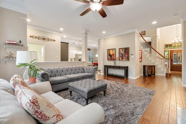 living room featuring a ceiling fan, wood finished floors, baseboards, ornamental molding, and ornate columns