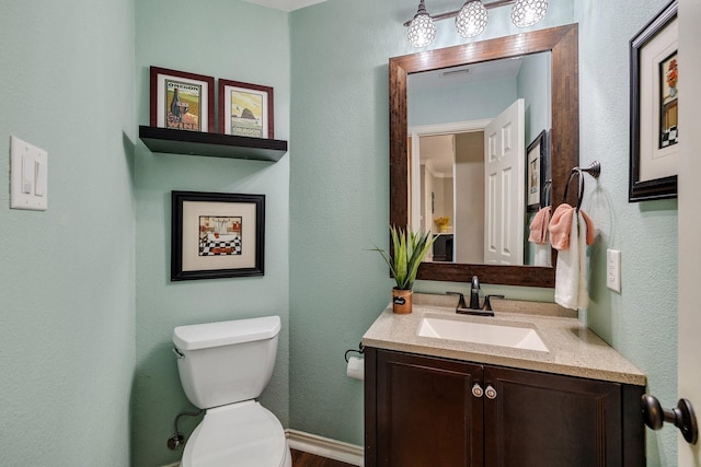 bathroom with vanity, a textured wall, wood finished floors, and toilet