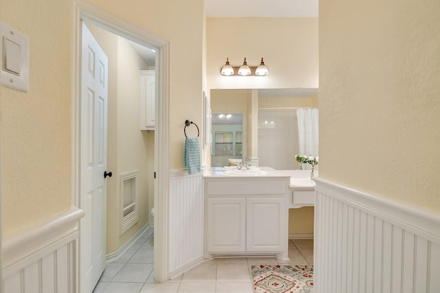 bathroom with a shower with curtain, wainscoting, tile patterned flooring, and vanity