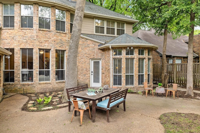 back of house with outdoor dining area, a patio area, fence, and roof with shingles
