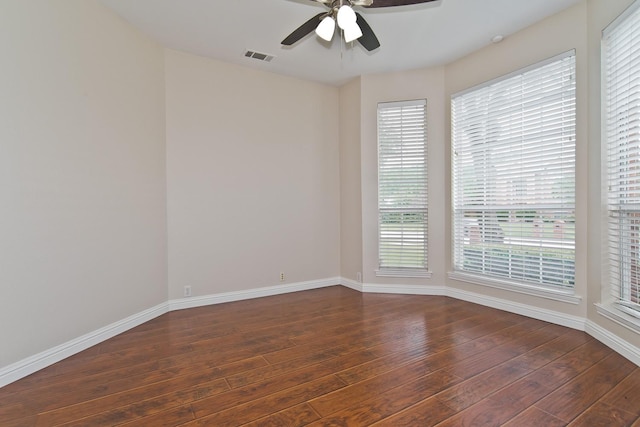 empty room with baseboards, a ceiling fan, hardwood / wood-style flooring, and visible vents