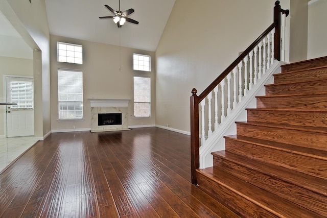 unfurnished living room featuring stairs, a ceiling fan, high vaulted ceiling, and hardwood / wood-style flooring