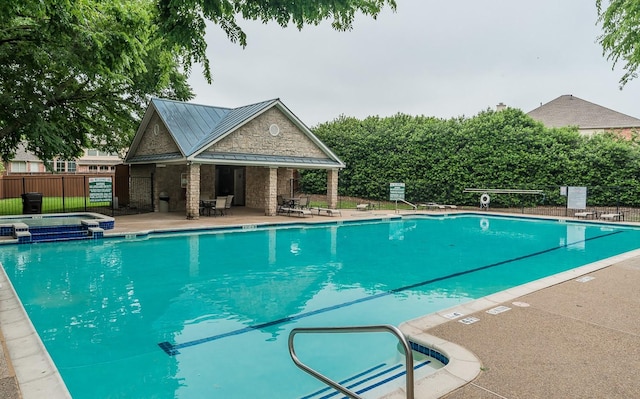 view of swimming pool featuring fence, an outdoor structure, a pool with connected hot tub, and a patio area