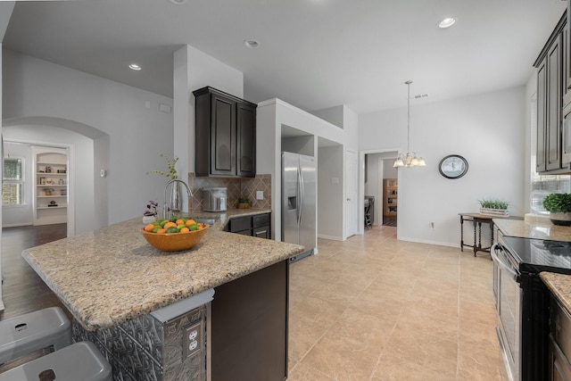 2308 Patriot Dr, Melissa, TX 75454 - kitchen with backsplash, appliances with stainless steel finishes, arched walkways, light stone countertops, and an inviting chandelier