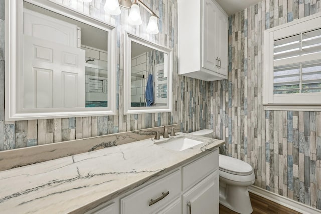 bathroom with vanity, wallpapered walls, toilet, and wood finished floors