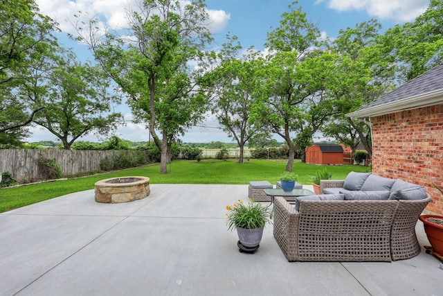 view of patio / terrace featuring a storage shed, an outbuilding, a fenced backyard, and an outdoor living space with a fire pit