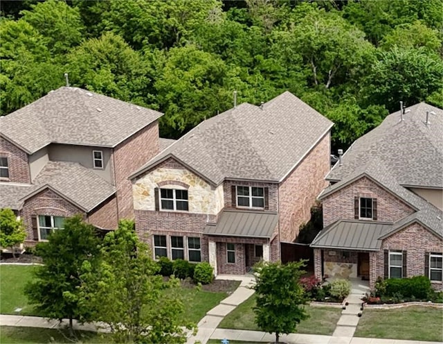 view of front of house with roof with shingles, a standing seam roof, and a front yard