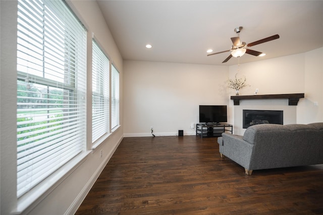 living area with a glass covered fireplace, baseboards, dark wood-style floors, recessed lighting, and a ceiling fan