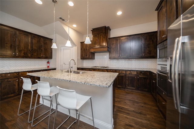kitchen featuring visible vents, tasteful backsplash, custom range hood, a sink, and stainless steel appliances
