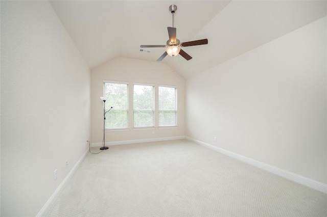 spare room featuring baseboards, ceiling fan, light carpet, and lofted ceiling