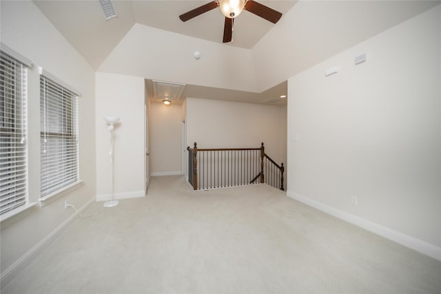 carpeted empty room featuring baseboards, ceiling fan, attic access, and visible vents