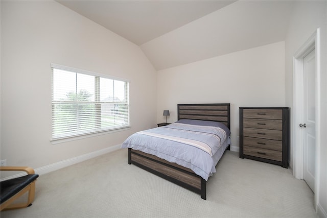 bedroom featuring baseboards, lofted ceiling, and light carpet
