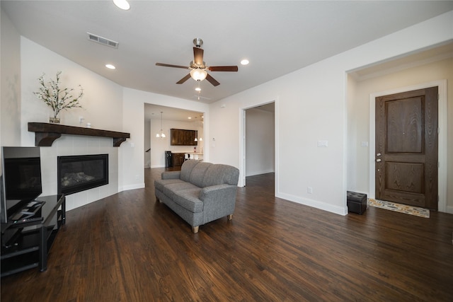 living room with visible vents, wood finished floors, a fireplace, baseboards, and a ceiling fan