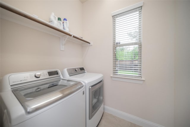 washroom with laundry area, baseboards, independent washer and dryer, and light tile patterned flooring