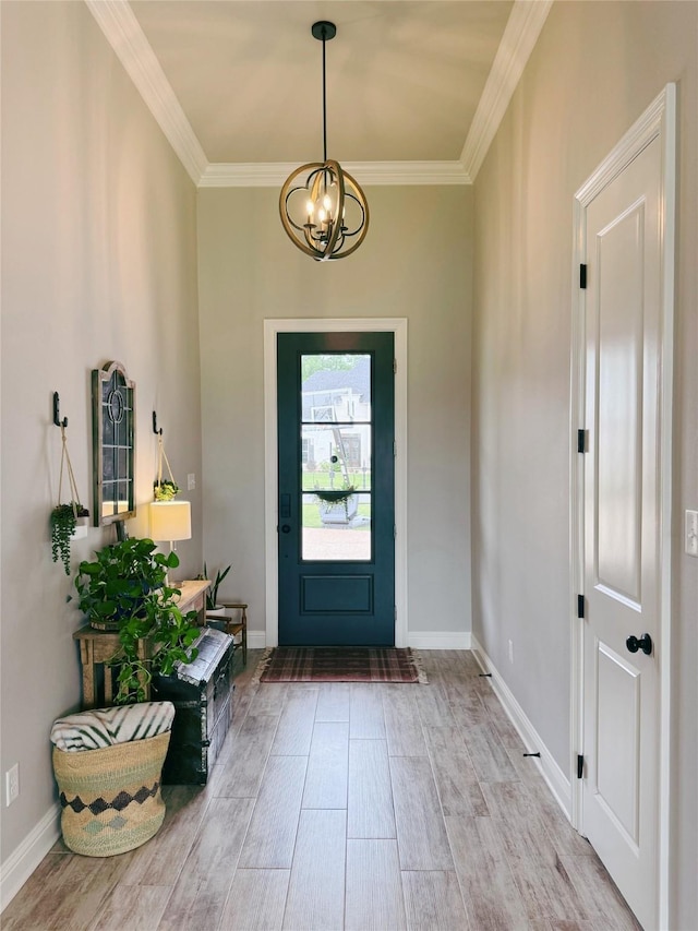 entryway featuring baseboards, ornamental molding, wood finished floors, and a chandelier