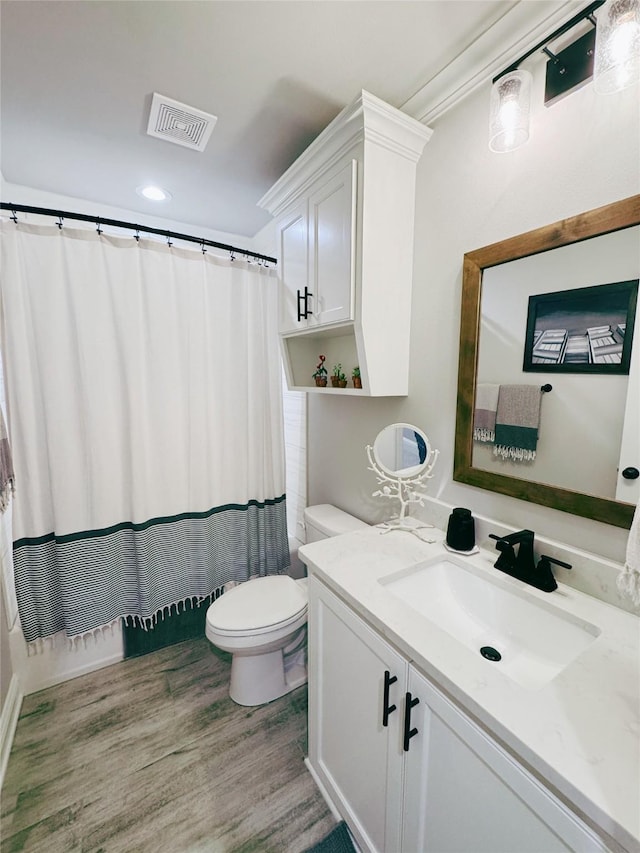 full bathroom featuring vanity, toilet, a shower with shower curtain, wood finished floors, and visible vents