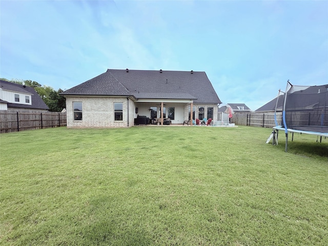 back of house featuring a fenced backyard, a trampoline, a lawn, and a patio