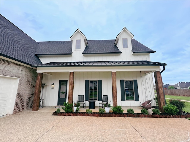 modern inspired farmhouse featuring covered porch, board and batten siding, a standing seam roof, metal roof, and a shingled roof