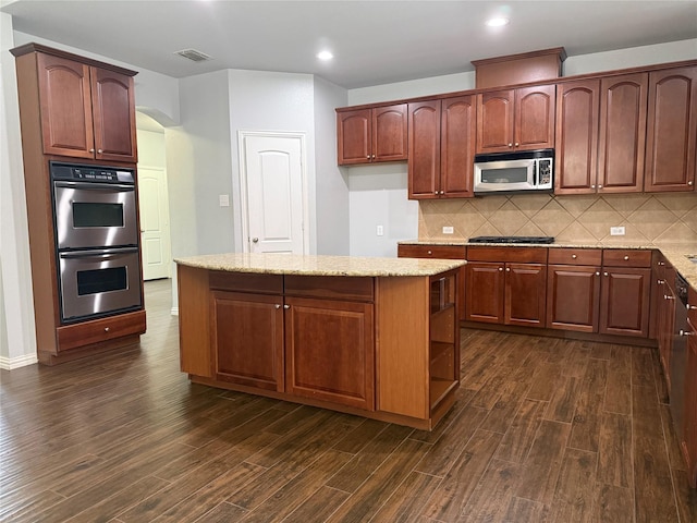 kitchen with dark wood-type flooring, appliances with stainless steel finishes, and light stone countertops