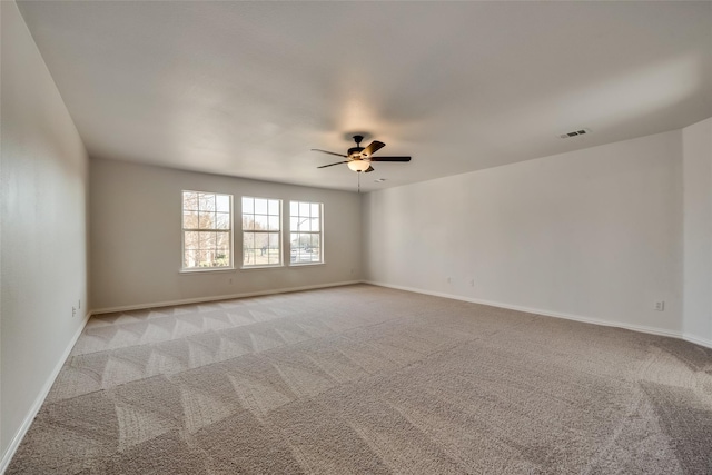 empty room with visible vents, baseboards, ceiling fan, and light colored carpet