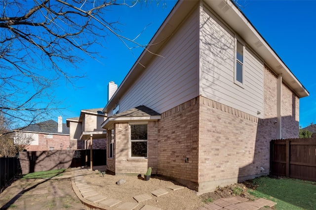 back of property with fence, a chimney, and brick siding