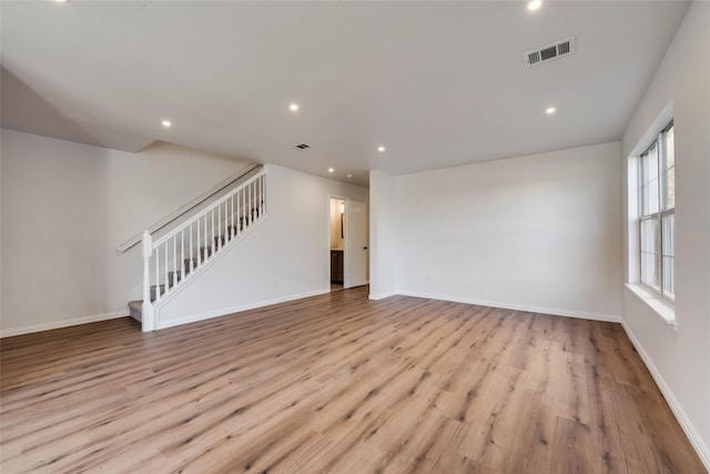 unfurnished living room with visible vents, recessed lighting, wood finished floors, and stairway