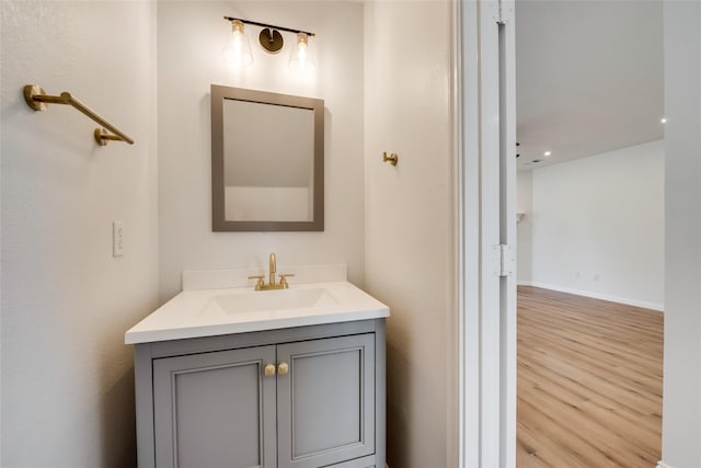 bathroom with vanity, recessed lighting, baseboards, and wood finished floors