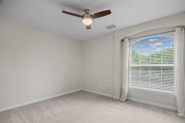 empty room with visible vents, a ceiling fan, baseboards, and light colored carpet