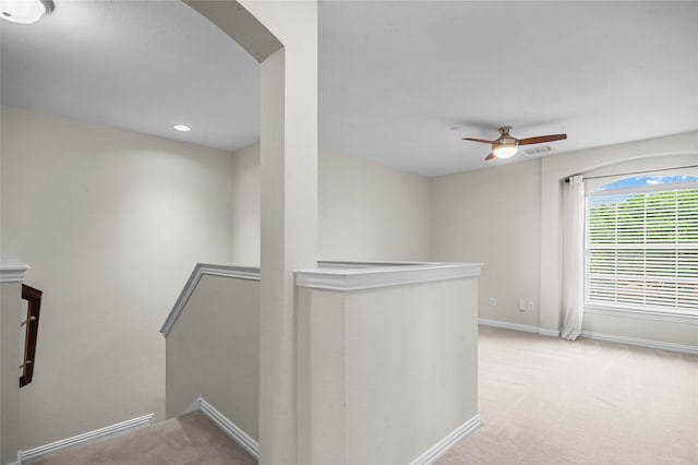 corridor featuring carpet floors, arched walkways, baseboards, an upstairs landing, and visible vents