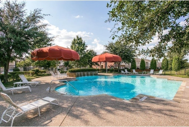 community pool with fence and a patio area