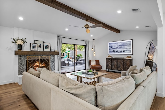 living room with visible vents, wood finished floors, baseboards, a warm lit fireplace, and recessed lighting