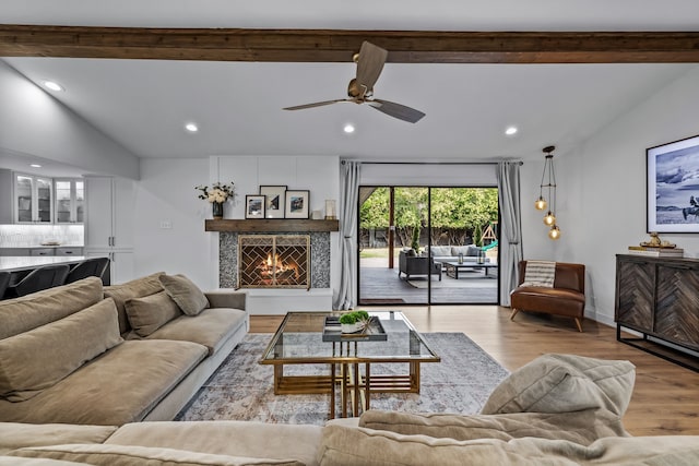 living area with recessed lighting, wood finished floors, and a warm lit fireplace