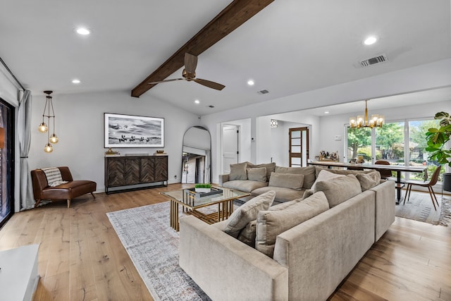 living area featuring lofted ceiling with beams, ceiling fan with notable chandelier, light wood finished floors, and visible vents