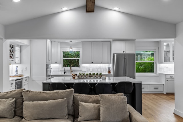 kitchen featuring open floor plan, light countertops, tasteful backsplash, light wood finished floors, and stainless steel appliances