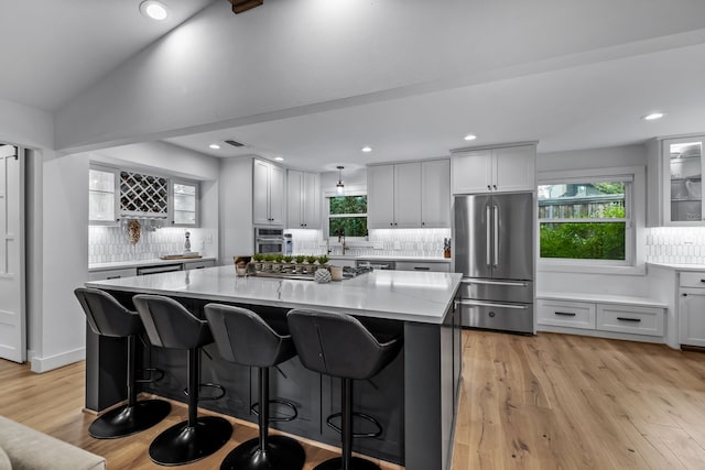 kitchen featuring decorative backsplash, a center island, light wood-style floors, a breakfast bar, and stainless steel appliances