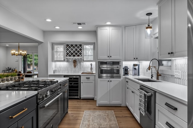 kitchen with a sink, appliances with stainless steel finishes, decorative backsplash, and wine cooler