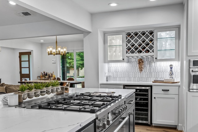 kitchen featuring decorative backsplash, beverage cooler, recessed lighting, a chandelier, and stainless steel appliances